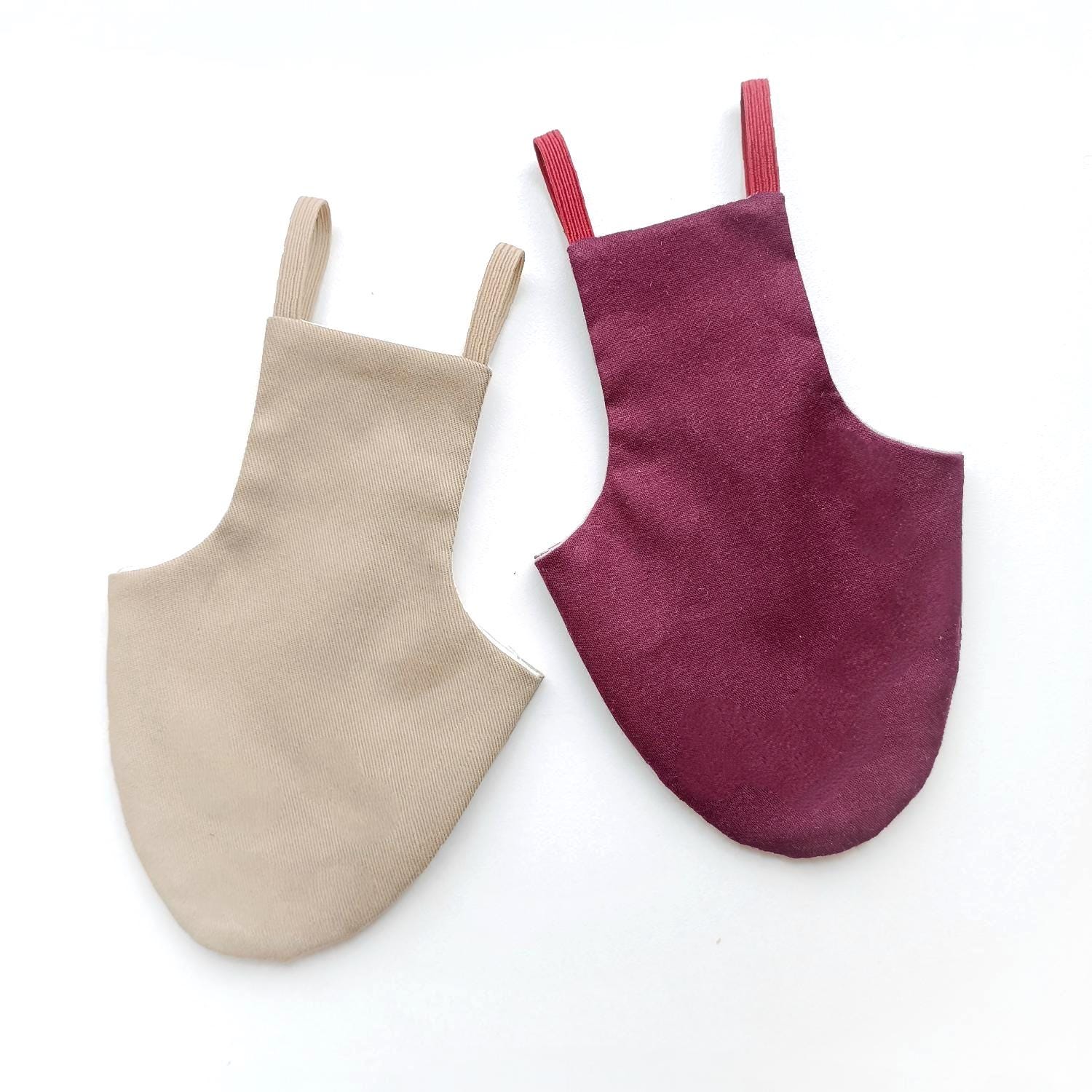 Two bird diapers or pigeon pants, one beige and one purple, on a white background